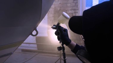 Garajda profesyonel bir adam (adam) bir mini-jet (spreyler) ile bir koruyucu takım dispenser ve koruyucu gözlük kullanarak yüzeye boya (seramik) uygulayarak yat (ulaşım) kapsar.