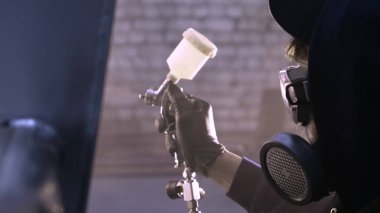 Garajda profesyonel bir adam (adam) bir mini-jet (spreyler) ile bir koruyucu takım dispenser ve koruyucu gözlük kullanarak yüzeye boya (seramik) uygulayarak yat (ulaşım) kapsar.