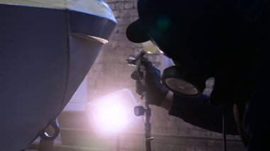 Garajda profesyonel bir adam (adam) bir mini-jet (spreyler) ile bir koruyucu takım dispenser ve koruyucu gözlük kullanarak yüzeye boya (seramik) uygulayarak yat (ulaşım) kapsar.