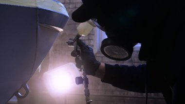 Garajda profesyonel bir adam (adam) bir mini-jet (spreyler) ile bir koruyucu takım dispenser ve koruyucu gözlük kullanarak yüzeye boya (seramik) uygulayarak yat (ulaşım) kapsar.