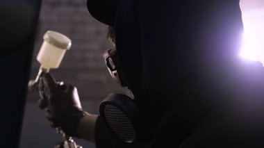 Garajda profesyonel bir adam (adam) bir mini-jet (spreyler) ile bir koruyucu takım dispenser ve koruyucu gözlük kullanarak yüzeye boya (seramik) uygulayarak yat (ulaşım) kapsar.