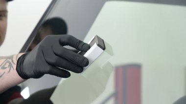 Profesyonel bir erkek (erkek) bir araba seramik ustası bir çekmece, güvenlik gözlükleri ve siyah eldiven bir fiber (sünger) bez kullanarak bir araba seramik koyar.