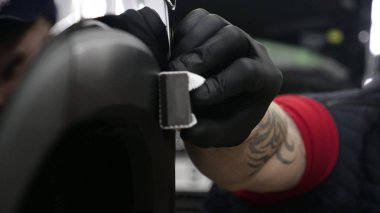 Profesyonel bir erkek (erkek) bir araba seramik ustası bir çekmece, güvenlik gözlükleri ve siyah eldiven bir fiber (sünger) bez kullanarak bir araba seramik koyar.