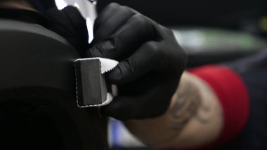 Profesyonel bir erkek (erkek) bir araba seramik ustası bir çekmece, güvenlik gözlükleri ve siyah eldiven bir fiber (sünger) bez kullanarak bir araba seramik koyar.