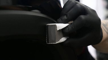 Profesyonel bir erkek (erkek) bir araba seramik ustası bir çekmece, güvenlik gözlükleri ve siyah eldiven bir fiber (sünger) bez kullanarak bir araba seramik koyar.