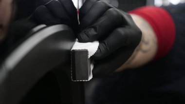 Profesyonel bir erkek (erkek) bir araba seramik ustası bir çekmece, güvenlik gözlükleri ve siyah eldiven bir fiber (sünger) bez kullanarak bir araba seramik koyar.