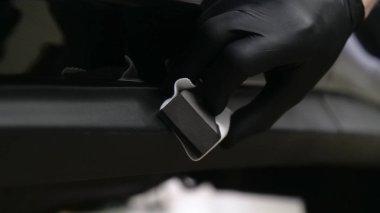 Profesyonel bir erkek (erkek) bir araba seramik ustası bir çekmece, güvenlik gözlükleri ve siyah eldiven bir fiber (sünger) bez kullanarak bir araba seramik koyar.