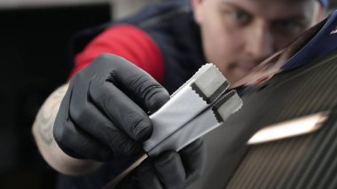 Profesyonel bir erkek (erkek) bir araba seramik ustası bir çekmece, güvenlik gözlükleri ve siyah eldiven bir fiber (sünger) bez kullanarak bir araba seramik koyar.