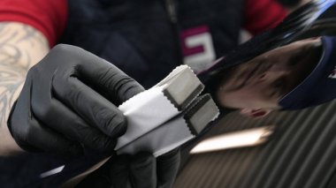 Profesyonel bir erkek (erkek) bir araba seramik ustası bir çekmece, güvenlik gözlükleri ve siyah eldiven bir fiber (sünger) bez kullanarak bir araba seramik koyar.