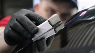 Profesyonel bir erkek (erkek) bir araba seramik ustası bir çekmece, güvenlik gözlükleri ve siyah eldiven bir fiber (sünger) bez kullanarak bir araba seramik koyar.