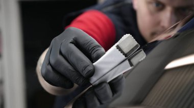 Profesyonel bir erkek (erkek) bir araba seramik ustası bir çekmece, güvenlik gözlükleri ve siyah eldiven bir fiber (sünger) bez kullanarak bir araba seramik koyar.