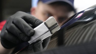 Profesyonel bir erkek (erkek) bir araba seramik ustası bir çekmece, güvenlik gözlükleri ve siyah eldiven bir fiber (sünger) bez kullanarak bir araba seramik koyar.