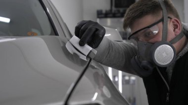 Profesyonel bir erkek (erkek) bir araba seramik ustası bir çekmece, güvenlik gözlükleri ve siyah eldiven bir fiber (sünger) bez kullanarak bir araba seramik koyar.