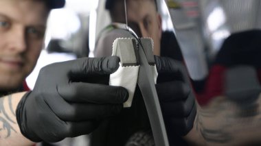 Profesyonel bir erkek (erkek) bir araba seramik ustası bir çekmece, güvenlik gözlükleri ve siyah eldiven bir fiber (sünger) bez kullanarak bir araba seramik koyar.