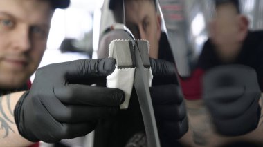 Profesyonel bir erkek (erkek) bir araba seramik ustası bir çekmece, güvenlik gözlükleri ve siyah eldiven bir fiber (sünger) bez kullanarak bir araba seramik koyar.