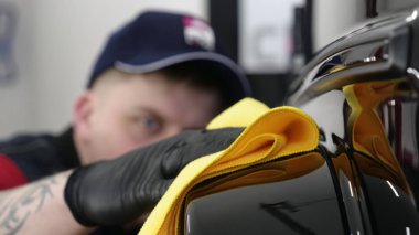 Profesyonel bir erkek (erkek) bir araba seramik ustası bir çekmece, güvenlik gözlükleri ve siyah eldiven bir fiber (sünger) bez kullanarak bir araba seramik koyar.