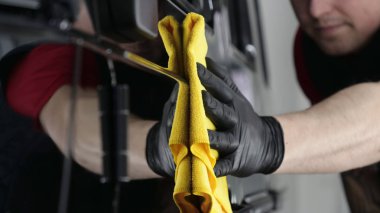 Profesyonel bir erkek (erkek) bir araba seramik ustası bir çekmece, güvenlik gözlükleri ve siyah eldiven bir fiber (sünger) bez kullanarak bir araba seramik koyar.