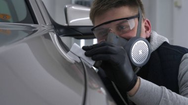 Profesyonel bir erkek (erkek) bir araba seramik ustası bir çekmece, güvenlik gözlükleri ve siyah eldiven bir fiber (sünger) bez kullanarak bir araba seramik koyar.