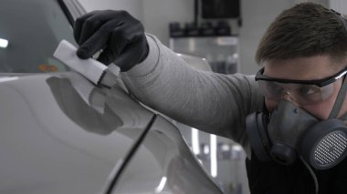 Profesyonel bir erkek (erkek) bir araba seramik ustası bir çekmece, güvenlik gözlükleri ve siyah eldiven bir fiber (sünger) bez kullanarak bir araba seramik koyar.