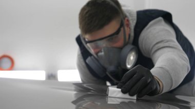 Profesyonel bir erkek (erkek) bir araba seramik ustası bir çekmece, güvenlik gözlükleri ve siyah eldiven bir fiber (sünger) bez kullanarak bir araba seramik koyar.