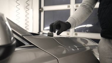 Profesyonel bir erkek (erkek) bir araba seramik ustası bir çekmece, güvenlik gözlükleri ve siyah eldiven bir fiber (sünger) bez kullanarak bir araba seramik koyar.