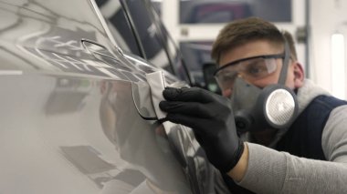 Profesyonel bir erkek (erkek) bir araba seramik ustası bir çekmece, güvenlik gözlükleri ve siyah eldiven bir fiber (sünger) bez kullanarak bir araba seramik koyar.