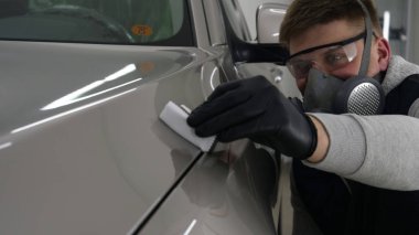 Profesyonel bir erkek (erkek) bir araba seramik ustası bir çekmece, güvenlik gözlükleri ve siyah eldiven bir fiber (sünger) bez kullanarak bir araba seramik koyar.