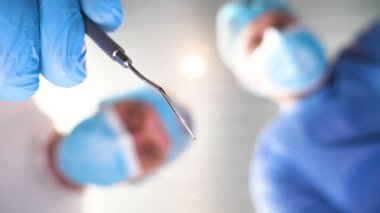 Hastanede, doktor ve doktor asistanı farklı tıbbi araçlar kullanarak tedavi işlemi gerçekleştirmek. Her iki doktor da başlıklarında ve eldivenleriyle cüppeli doktorlar. Kavramı: Diş hekimleri.