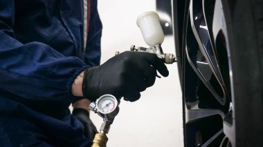 Elinde sprey tabancaları ile çalışan üniforma lı profesyonel ve koruyucu gözlüklü bir solunum cihazı arabanın farklı yerlerine boya (seramik) koyar, elinde bir klasör ile el feneri servis edilebilirlik için bir araba motoru kontrol eder. Kavram 