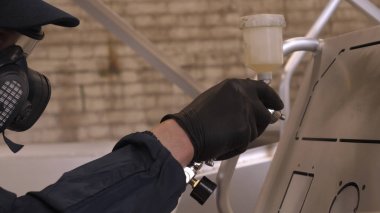 Profesyonel adam (adam) bir garaj (hizmet) bir kazak giymiş çalışma giysileri bir boya tabancası (sprey tabanca) kurar ve boyama başlar (seramik bir tabaka koyarak) bir yat.