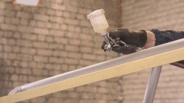 Profesyonel adam (adam) bir garaj (hizmet) bir kazak giymiş çalışma giysileri bir boya tabancası (sprey tabanca) kurar ve boyama başlar (seramik bir tabaka koyarak) bir yat.