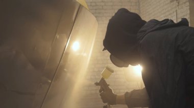 Profesyonel adam (adam) bir garaj (hizmet) bir kazak giymiş çalışma giysileri bir boya tabancası (sprey tabanca) kurar ve boyama başlar (seramik bir tabaka koyarak) bir yat.