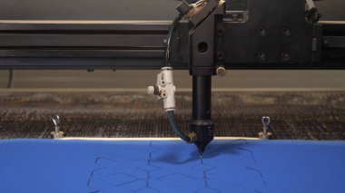 Bir endüstriyel Konfeksiyon fabrikasında, özel bir lazer kesme kumaş belirli Tekstil parçaları keser. Kavramı: lazer makine, haç, bir fabrikada çalışmak, otomatik kesme.