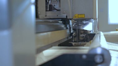 Endüstriyel konfeksiyon fabrikası, özel bir Lazer Kesme Kumaş bazı tekstil parçaları keser. Kavramı: Lazer makinesi, Haçlar, Bir fabrikada çalışma, Otomatik kesim.