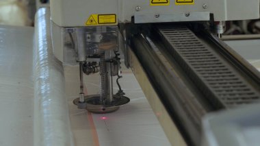 Endüstriyel konfeksiyon fabrikası, özel bir Lazer Kesme Kumaş bazı tekstil parçaları keser. Kavramı: Lazer makinesi, Haçlar, Bir fabrikada çalışma, Otomatik kesim.