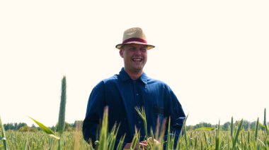 Genç bir adam portresi (adam) çalışan bir üniforma ve buğday ve saman etrafında bir alanın ortasında bir hasır şapka, etrafında çalışan ve olgunluk için buğday kontrol, bir gömlek ve hasır şapka ısı alanı temiz hava solur ve özgür hissediyor. 