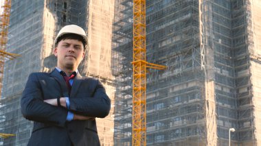 Oluşturucu veya mühendis, duruyor onun binaları, seyir sırt ile beyaz bir miğfer ve Evet, bir gökdelen bir takım elbise