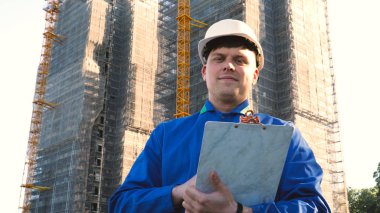 Oluşturucu veya mühendis, duruyor onun binaları, seyir sırt ile beyaz bir miğfer ve Evet, bir gökdelen bir takım elbise