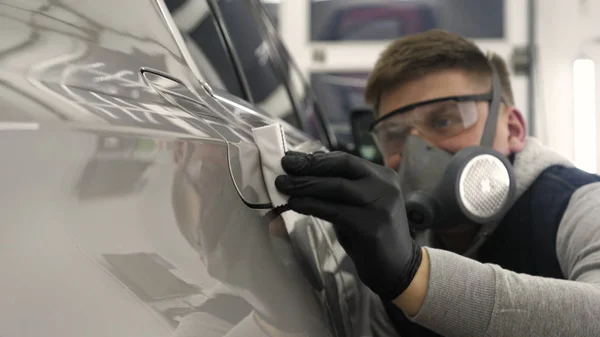 Profesyonel bir erkek (erkek) bir araba seramik ustası bir çekmece, güvenlik gözlükleri ve siyah eldiven bir fiber (sünger) bez kullanarak bir araba seramik koyar.