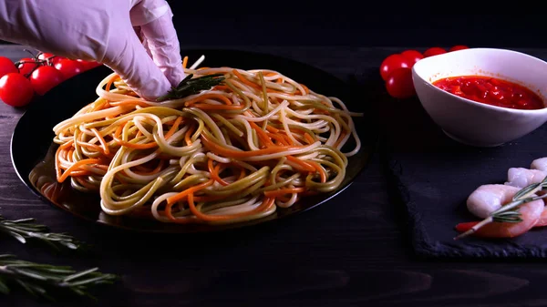 Cooked dish at home (in a restaurant) chef opens (removes) the lid from the pan. It can be seen in her pasta (noodles) differently colored,the chef decorates the finished pasta dish with grated Parmesan cheese on a kitchen grater and adding the sauce