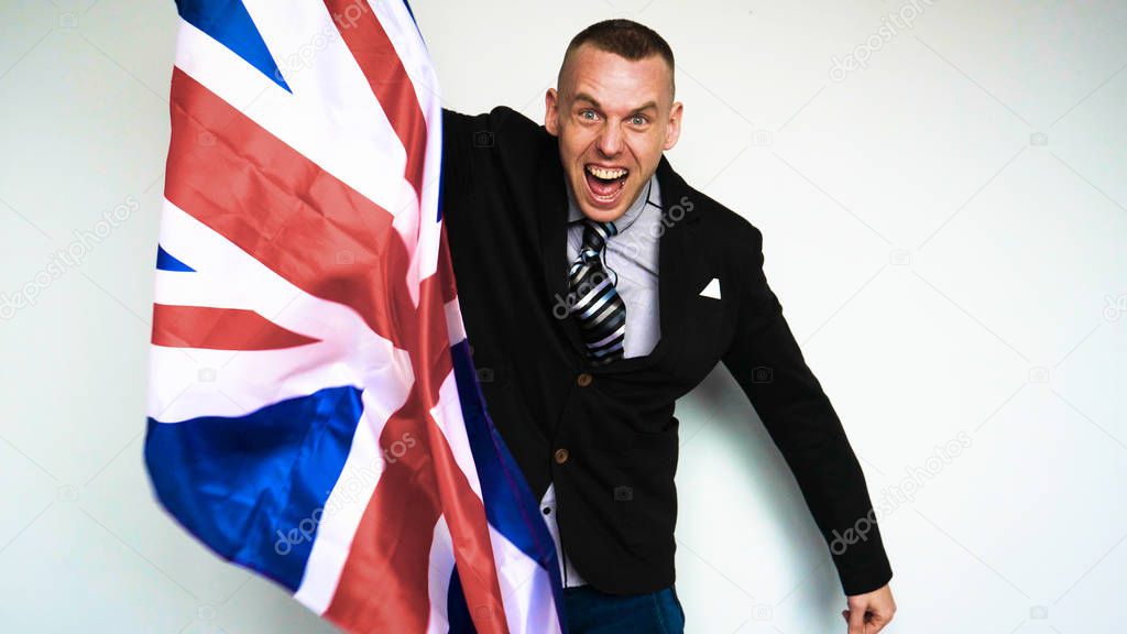 Fan of the United Kingdom of Great Britain (Englishman) on emotions holding a flag in his hands pleased with what is happening. Concept of: Brexit Out, Victory, Angry.