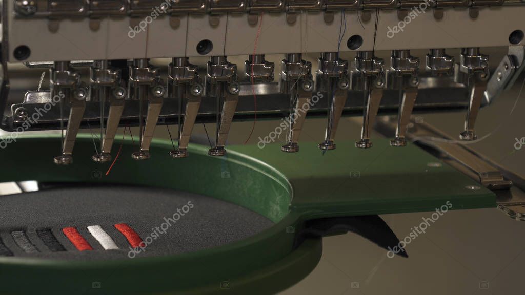 A sewing machine embroiders various companies and engravings. Concept of: Automated work, Sewing machine, Engraving, Thread, Fabric, Needle.