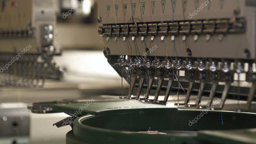 A sewing machine embroiders various companies and engravings. Concept of: Automated work, Sewing machine, Engraving, Thread, Fabric, Needle.