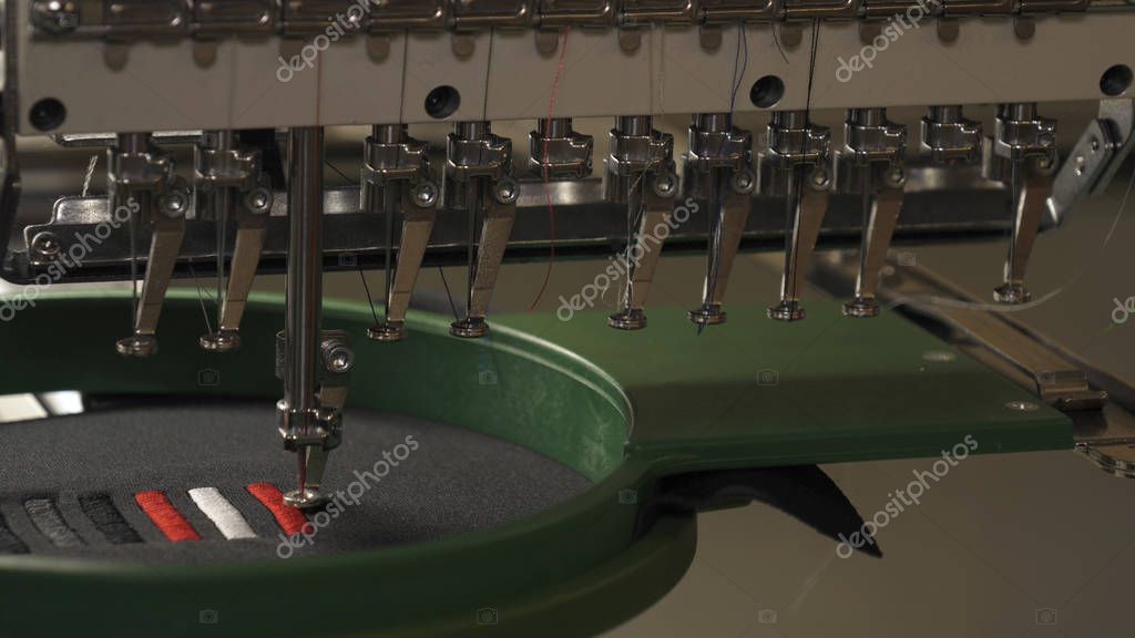 A sewing machine embroiders various companies and engravings. Concept of: Automated work, Sewing machine, Engraving, Thread, Fabric, Needle.