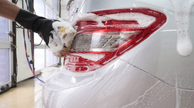 Profesyonel, arabayı siyah eldivenlerle, sünger ve köpükle yıkar. Konsept: Oto yıkama, sünger, köpük, su, profesyonel, iş.