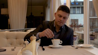 Bir restoranda genç yakışıklı bir adam (adam) reçel ile krep yemek bir takım elbise oturur. Kavramı: İyi ruh hali, Lezzetli gıda, Krep, Kahve, Çay, İş adamı, Kahvaltı, Çilek, Lifestyle.