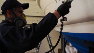 Yat teknisyeni pervaneyi kimyasal sprey (boya) temizleyicisini kirden temizler. Konsept: Yeni teknik, Kimya, Profesional, Boya, Solunum, Maske, Yat Kulübü.