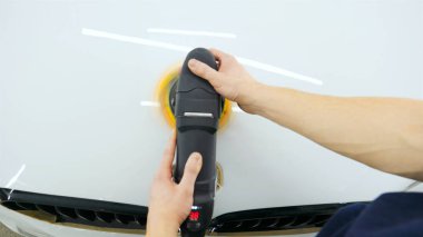 Profesyonel adam (adam) ile kulaklık ve çalışan bir üniforma parlatma aracı ile araba gövdesi parlatır. Konsept: Master Class, araba ferahlık, garaj Servisi, özel araçlar.