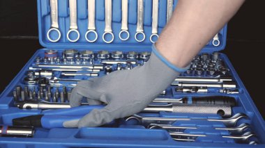 Usta, inşaatçı veya tamirci elinde bir kaliper tutar, özel bir takım elbise, ölçümler sarı bir bant ölçüsü, siyah bir arka plan.