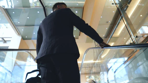 Young handsome guy businessman in a suit, (man) climbs the stairs with a black bag in his hands. Concept: business, suit, guy, man, bag, businessman.